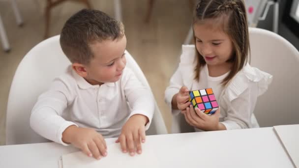 愛らしい女の子と男の子遊びます色パズルキューブ座っています上のテーブルの上に幼稚園 — ストック動画