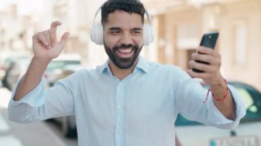 Young arab man listening to music and dancing at street