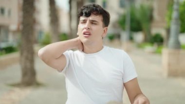 Non binary man using handfan suffering for hot at park