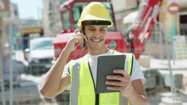 Genç İspanyol mimar parkta dokunmatik ped kullanarak akıllı telefondan konuşuyor.