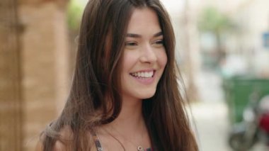 Young beautiful hispanic woman smiling confident looking to the side at street