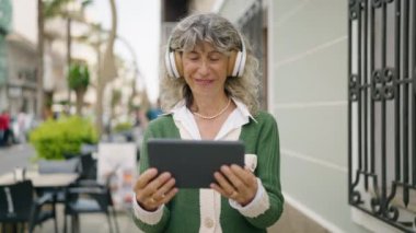 Orta yaşlı kadın gülümsüyor. Caddedeki touchpad 'de video izlerken kendinden emin.