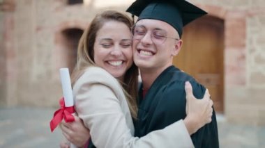Man and woman mother and son hugging each other celebrating graduation at university