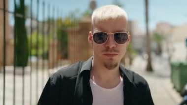 Sokakta ciddi bir ifadeyle duran beyaz bir genç.