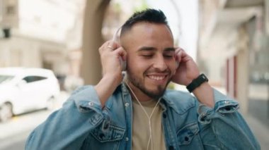 Sokakta müzik dinlerken kendinden emin gülümseyen İspanyol genç adam.