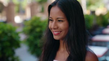 Genç ve güzel bir kadın gülümsüyor. Kendinden emin bir şekilde caddeye bakıyor.