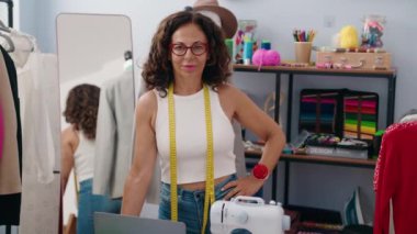 Middle age woman tailor smiling confident standing at clothing factory