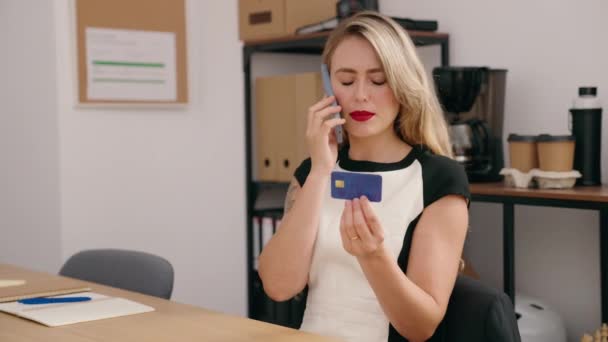 惊慌失措的女商人拿着信用卡在办公室里用智能手机交谈 — 图库视频影像