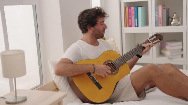 Pemuda Hispanik Bermain Gitar Klasik Duduk Tempat Tidur Kamar Tidur — Stok Video