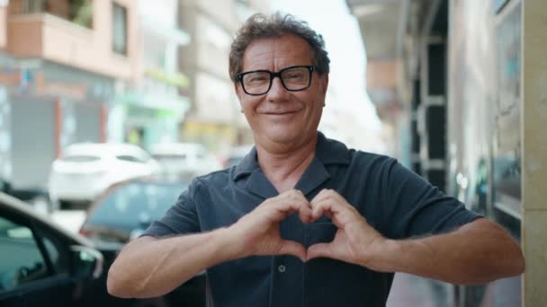 Hombre Mediana Edad Sonriendo Confiado Haciendo Gesto Corazón Con Las — Vídeos de Stock