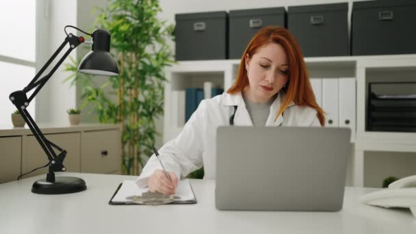 Young Redhead Woman Wearing Doctor Uniform Working Clinic — Stockvideo