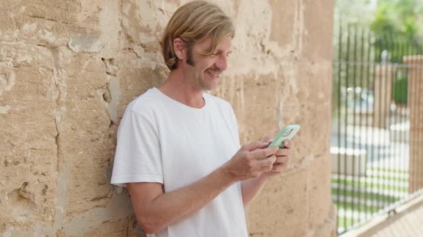 Pemuda Pirang Tersenyum Percaya Diri Menggunakan Smartphone Jalan — Stok Video