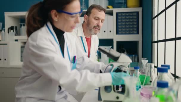 Laboratóriumban Dolgozó Férfi Női Tudósok Mikroszkóppal — Stock videók