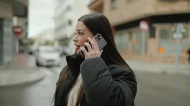 Genç İspanyol kadın gülümsüyor. Kendine güveniyor. Akıllı telefondan konuşuyor.