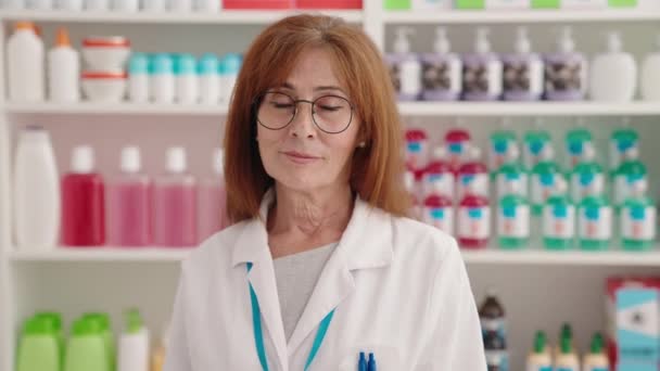 中年女性薬剤師笑顔自信を持って保持薬瓶に薬局 — ストック動画