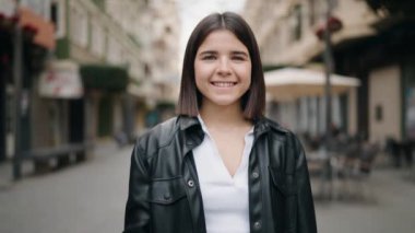 Young hispanic woman smiling confident using professional camera at street