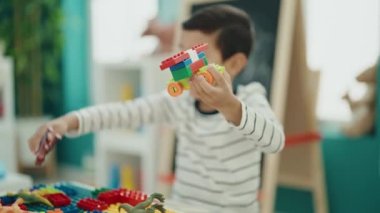 Anaokulundaki masada oturan, inşaat bloklarıyla oynayan sevimli İspanyol çocuk.
