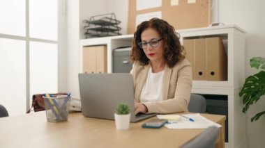 Middle age woman business worker using laptop and smartphone at office