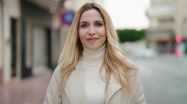 Sokakta profesyonel kamera kullanan, kendine güvenen genç sarışın kadın.