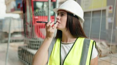 Young beautiful hispanic woman architect smiling confident talking on smartphone at street