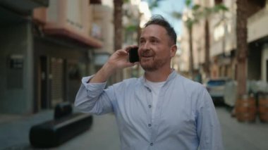 Kafkasyalı genç adam gülümsüyor. Kendine güvenen caddedeki akıllı telefondan konuşuyor.