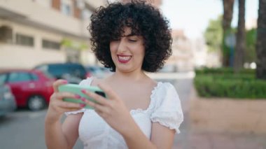 Young middle east woman smiling confident playing video game at street