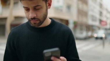 Genç Arap adam gülümsüyor, kendinden emin bir şekilde caddedeki akıllı telefondan konuşuyor.