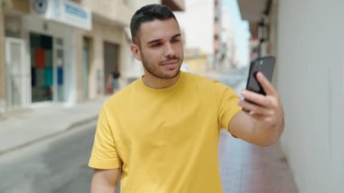 Young hispanic man smiling confident having video call at street