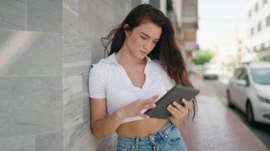 Young hispanic woman smiling confident using touchpad at street