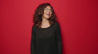 Middle age woman smiling confident standing over red background
