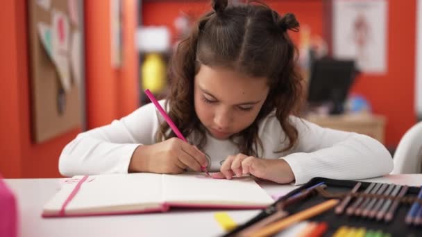Adorable Hispanic Girl Student Sitting Table Drawing Notebook Classroom — Vídeos de Stock