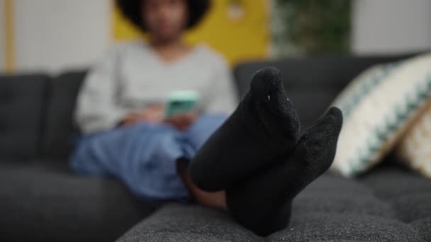 Afroamerikanerin Sitzt Mit Smartphone Hause Auf Sofa — Stockvideo