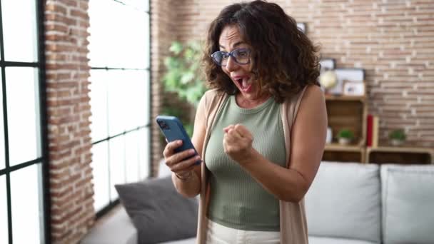 Middle Age Hispanic Woman Using Smartphone Celebrating — Stock video