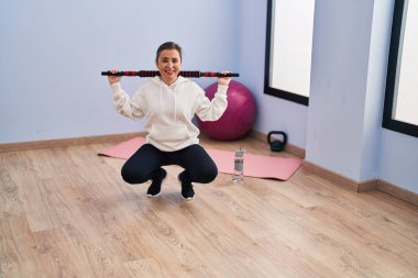 Middle age woman smiling confident training using bar at sport center