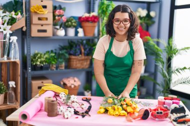 Young woman florist smiling confident prepare bouquet of flowers at florist