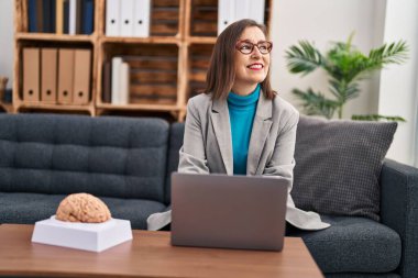 Middle age woman psychologist smiling confident using laptop at psychology center