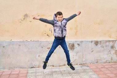 Blond child smiling confident jumping at street