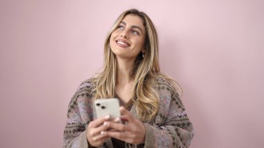 Young blonde woman smiling confident using smartphone over isolated pink background