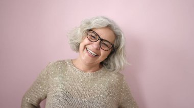 Middle age woman with grey hair smiling confident over isolated pink background