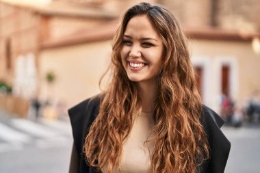 Young beautiful hispanic woman smiling confident looking to the side at street