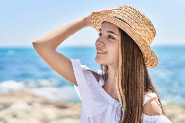 Adorable girl tourist smiling confident wearing summer hat at seaside