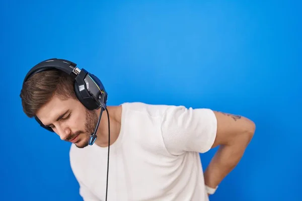 有胡子的西班牙裔男人 戴着耳机听音乐 用手触摸 肌肉疼痛 — 图库照片