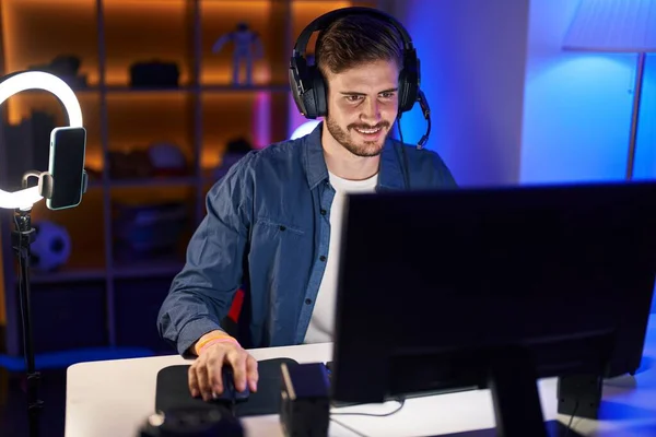stock image Young caucasian man streamer playing video game using computer at gaming room