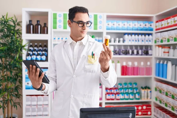 Giovane Farmacista Uomo Ispanico Utilizzando Touchpad Possesso Pillole Bottiglia Farmacia — Foto Stock