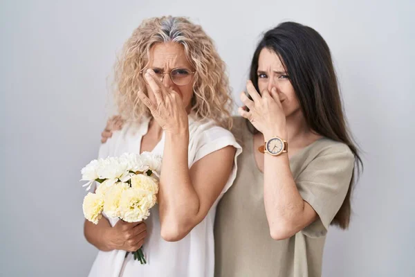 母親と娘の白い花の花束を保持何か臭いと嫌な 耐え難い匂い 鼻の上に指で息を保持臭い 臭いが悪い — ストック写真