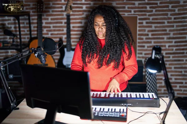 stock image Plus size hispanic woman playing piano at music studio skeptic and nervous, frowning upset because of problem. negative person. 