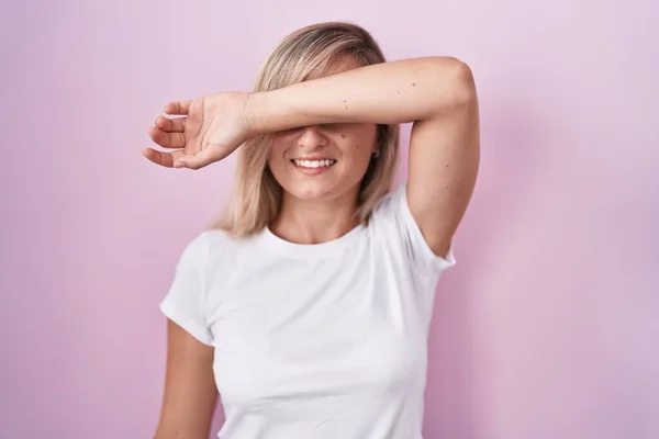 Young Blonde Woman Standing Pink Background Covering Eyes Arm Smiling — Fotografia de Stock