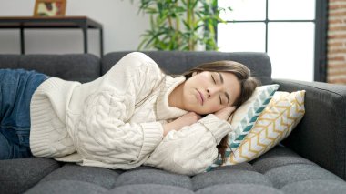 Young beautiful hispanic woman lying on sofa sleeping at home