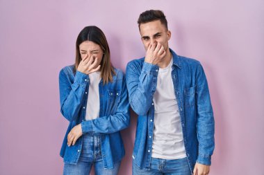 Pembe arka planda duran genç İspanyol çift pis ve iğrenç bir koku alıyor. Nefeslerini burunlarında tutuyorlar. Kötü kokuyor. 