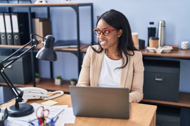 Ofiste çalışan genç Afro-Amerikan iş kadını laptopu kullanıyor.